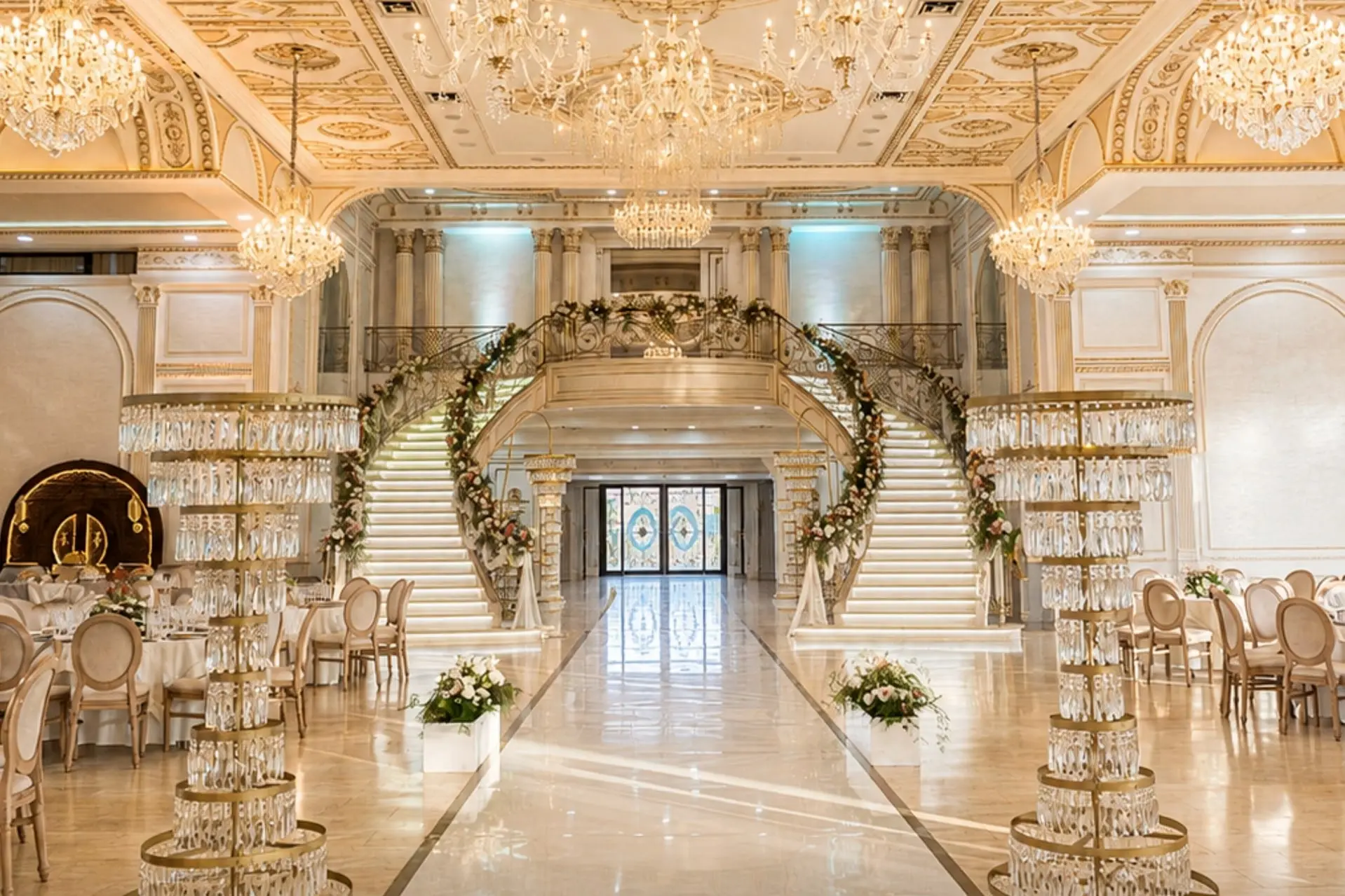 Curved double staircase dressed with floral garlands, crystal columns, gilded ceiling