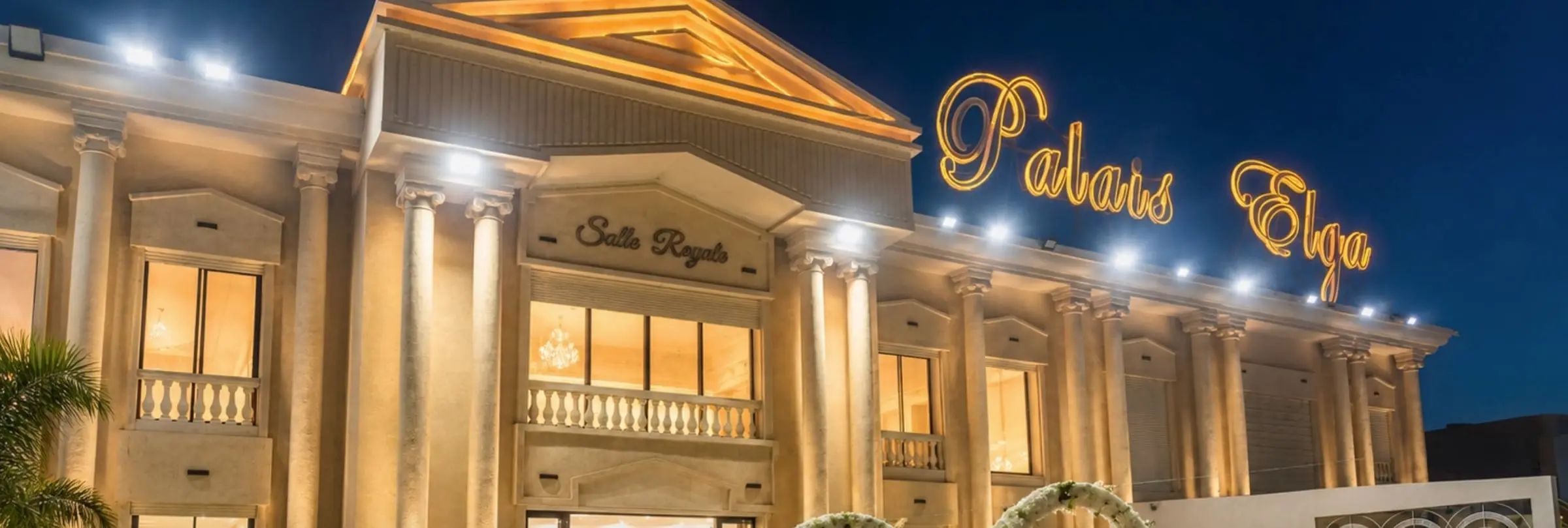 الواجهة في الساعة الزرقاء ولافتة «Palais Elga» مضاءة