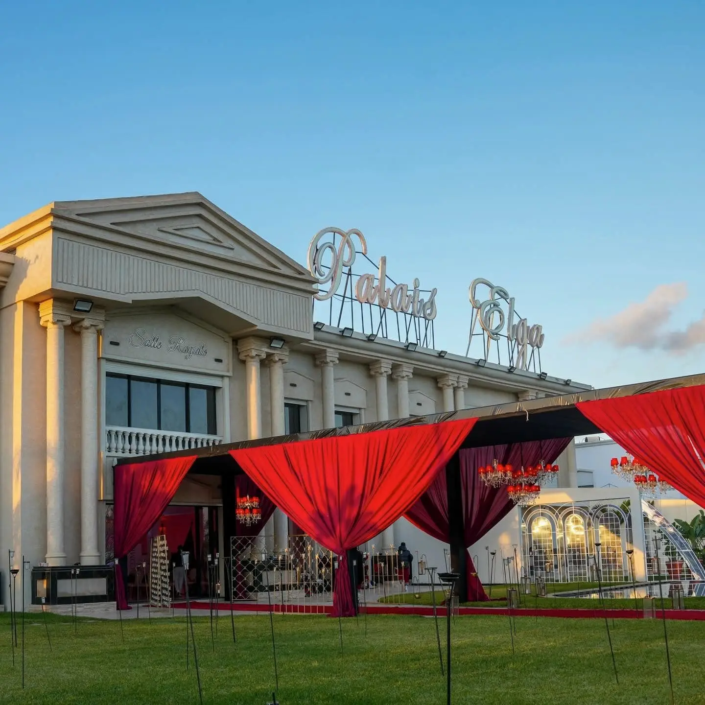 Golden-hour façade: pediment engraved “Salle Royale”, red-draped entrance pavilion