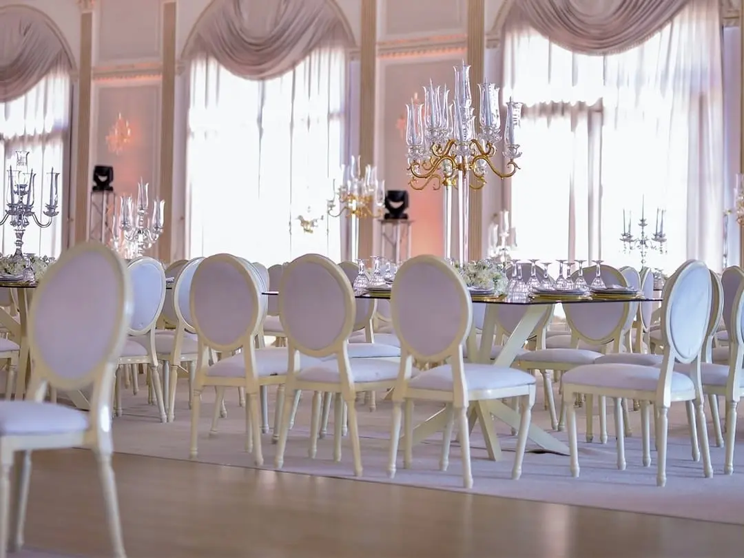 Tables drapées de blanc à la lumière du jour sous les fenêtres cintrées à rideaux