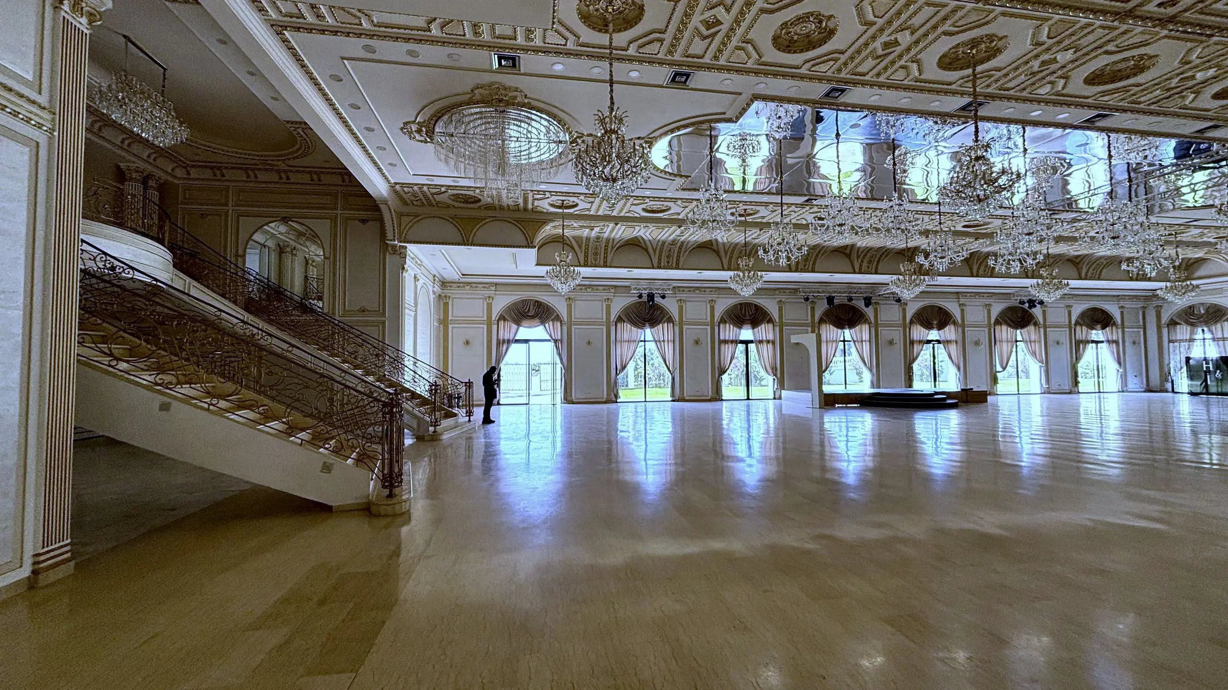 La Salle Royale vide : plafond doré, hautes fenêtres cintrées, sol poli, escalier à gauche