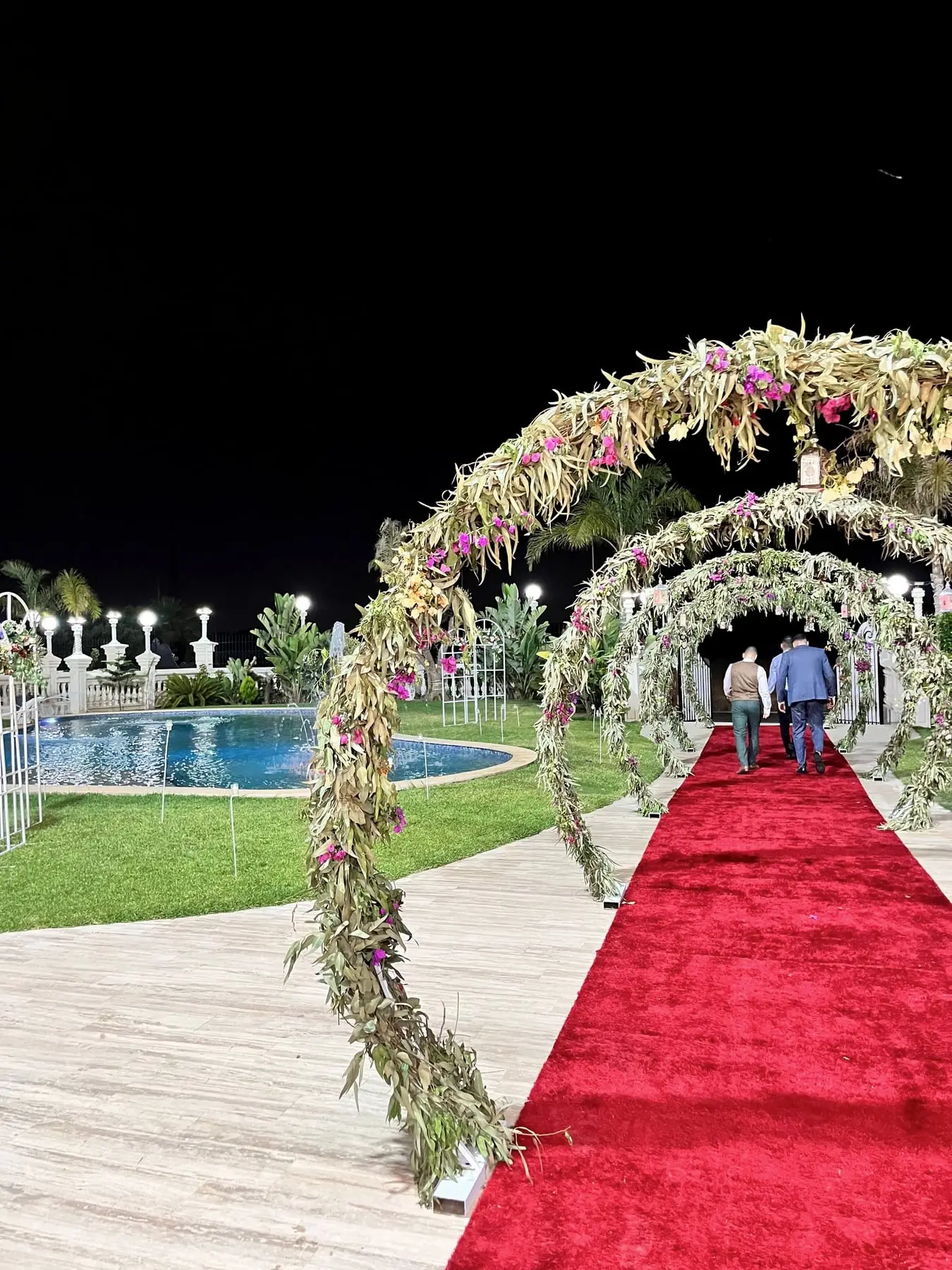 Tapis rouge sous des arches fleuries le long de la piscine, la nuit